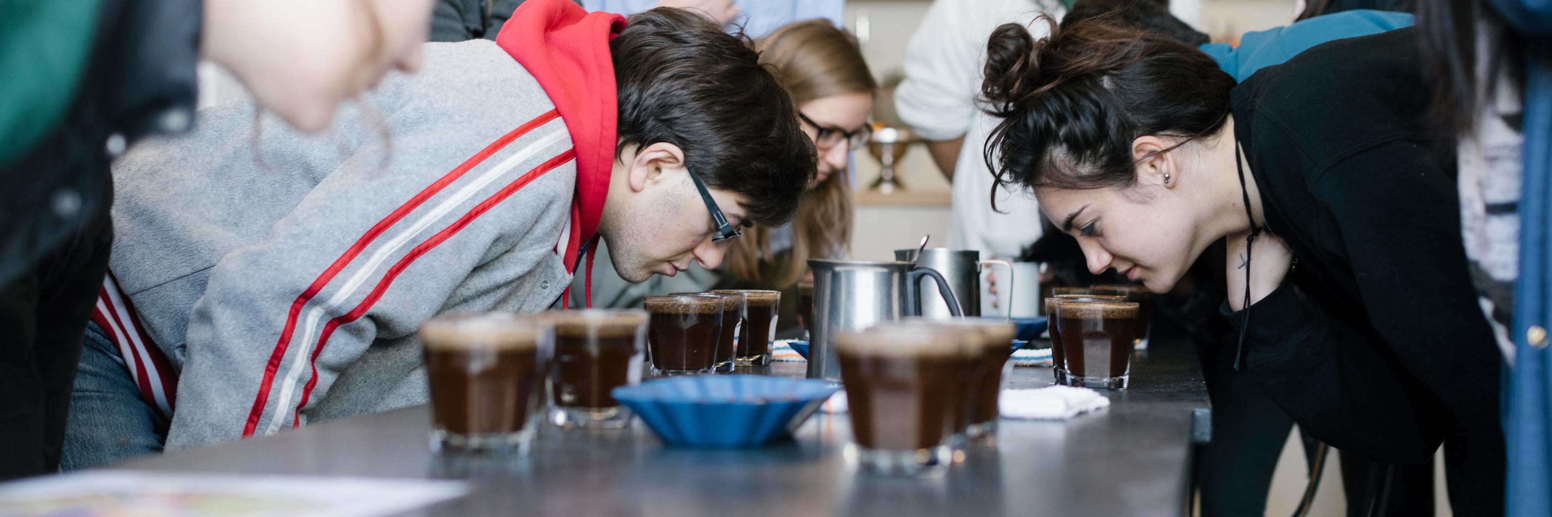 Students smelling various samples of coffee at a tasting event.