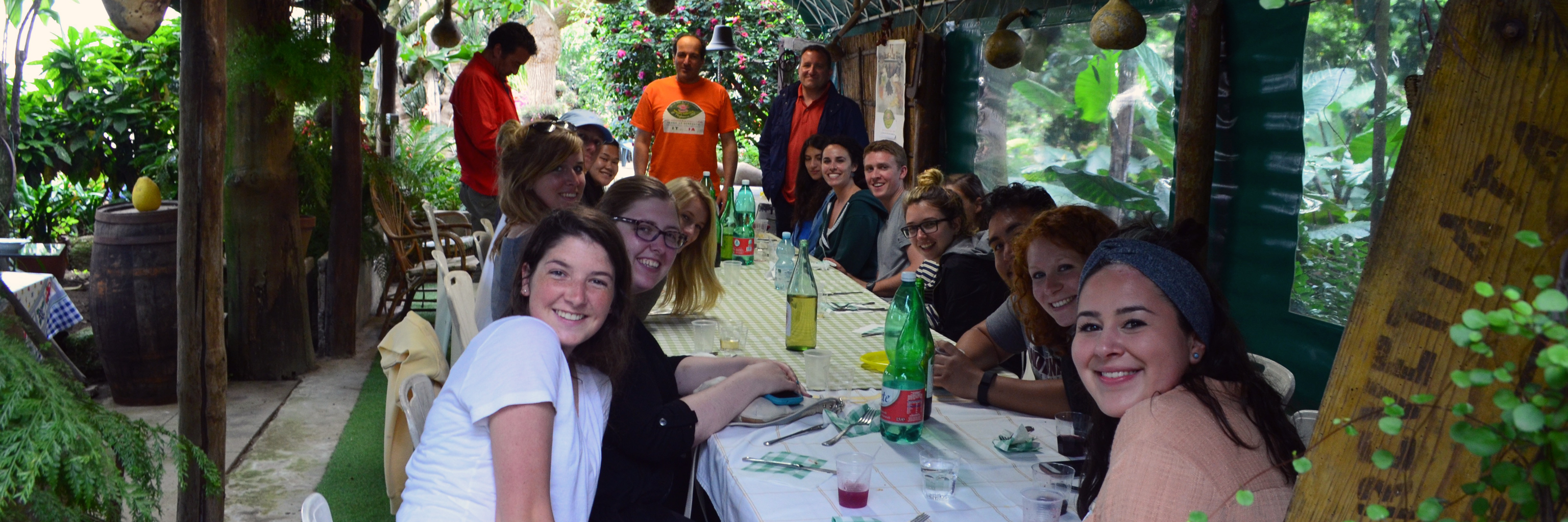 Students and faculty smiling around a long dining table abroad. 